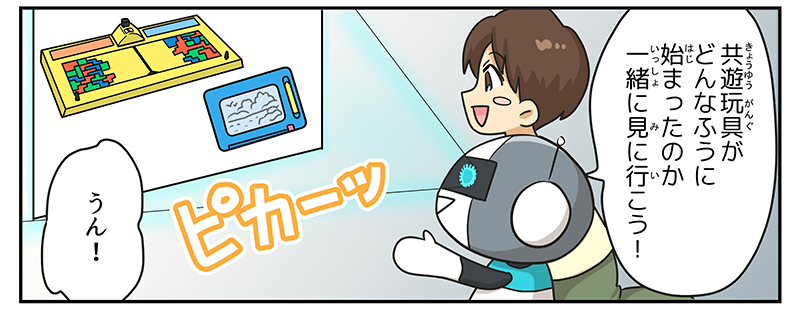 ロボットがキョウユウガングがどんなふうに始まったのか一緒に見に行こう！と言うと、目がぴかーっと光ってプロジェクターのようにキョウユウガング初期の２商品、テトリスとハンディーせんせい、の画像を部屋の壁に映し出しています、男の子もうん！と答えています